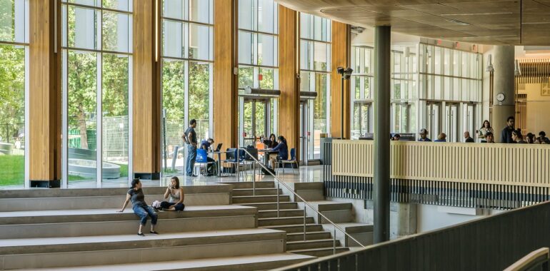 Students sitting on the stairs of a university offering a scokiolgy degree