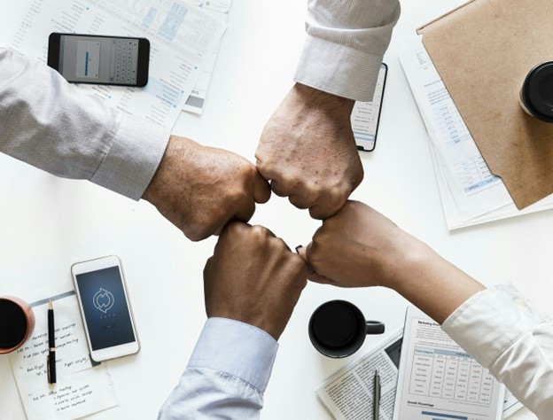 Professionals from colleges with human resources degrees in Illinois fist bumping.